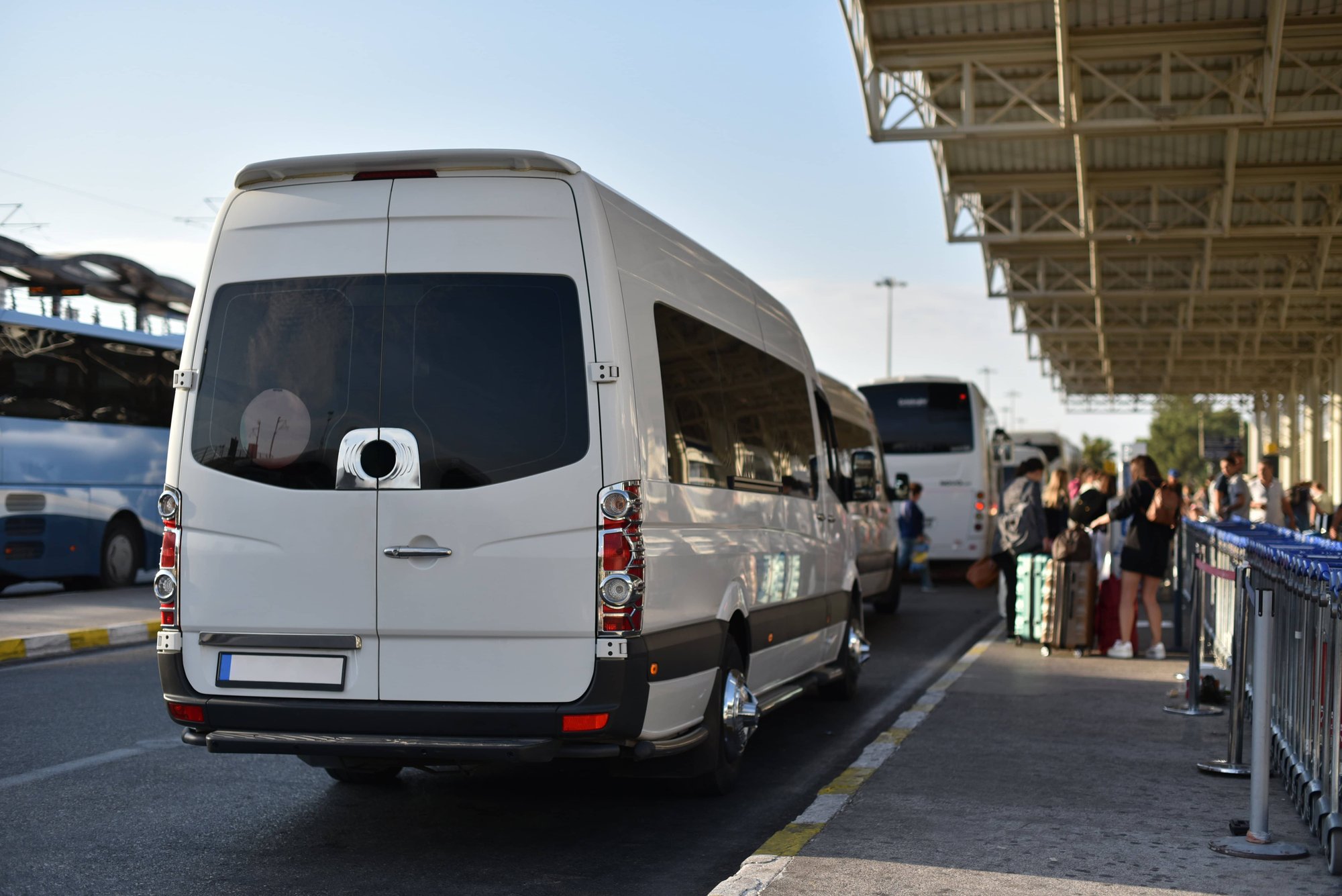 white paratransit vehicle parked at a terminal awaiting passengers