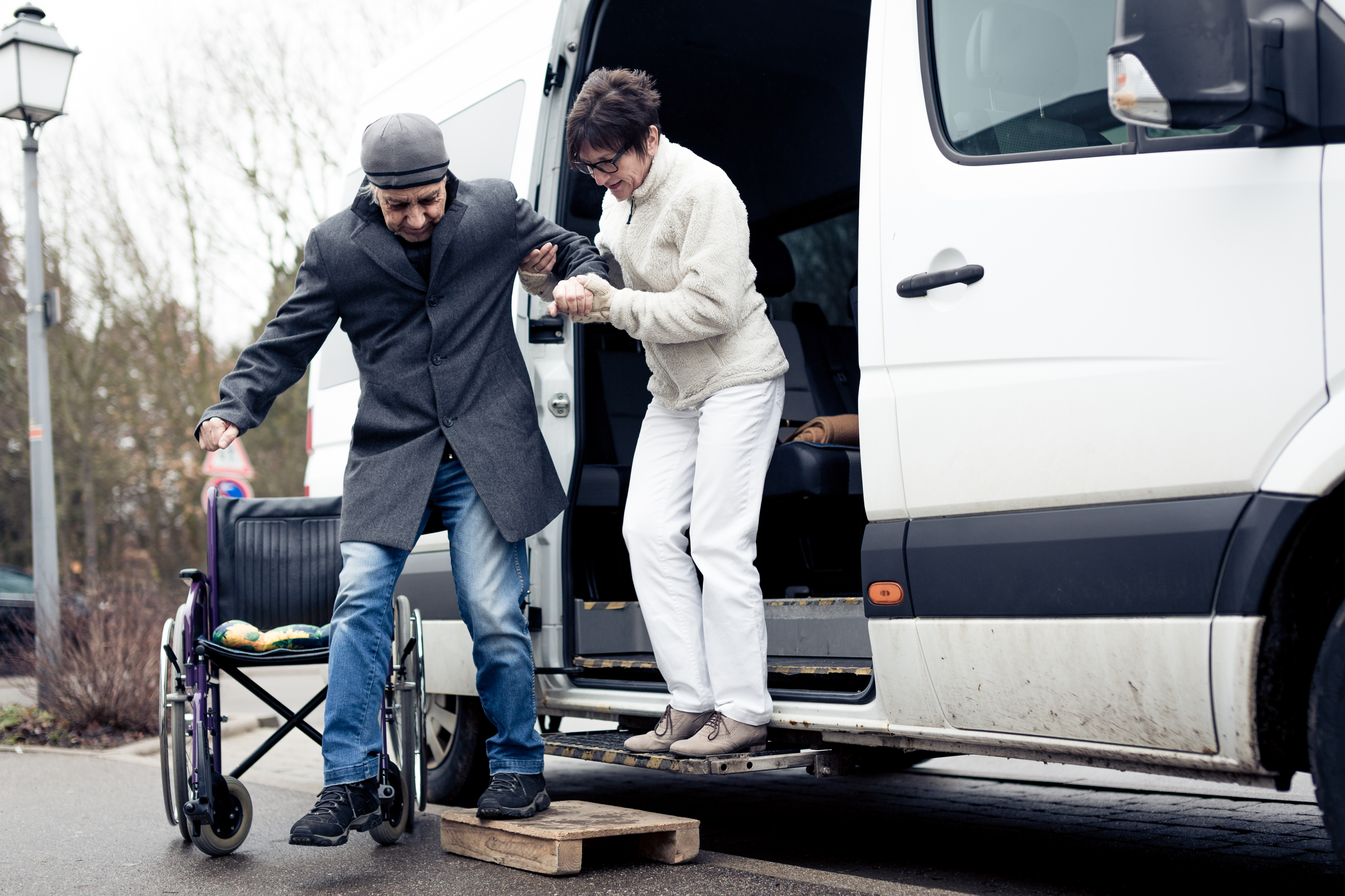 Transportation driver helping rider into their wheelchair.